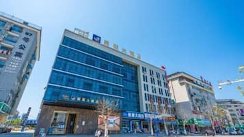 A modern hotel with a glass facade, multiple floors, and a prominent entrance.