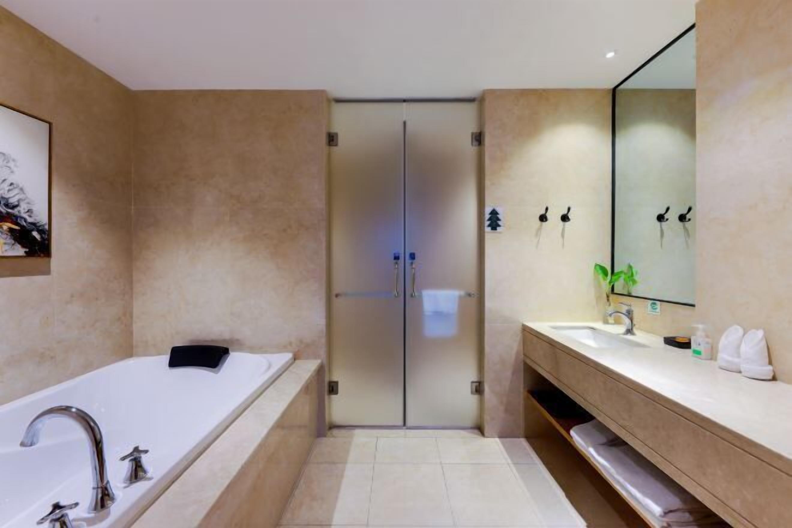 Une salle de bain moderne dotée d’une grande baignoire, d’un meuble-lavabo avec miroir et d’un espace douche.