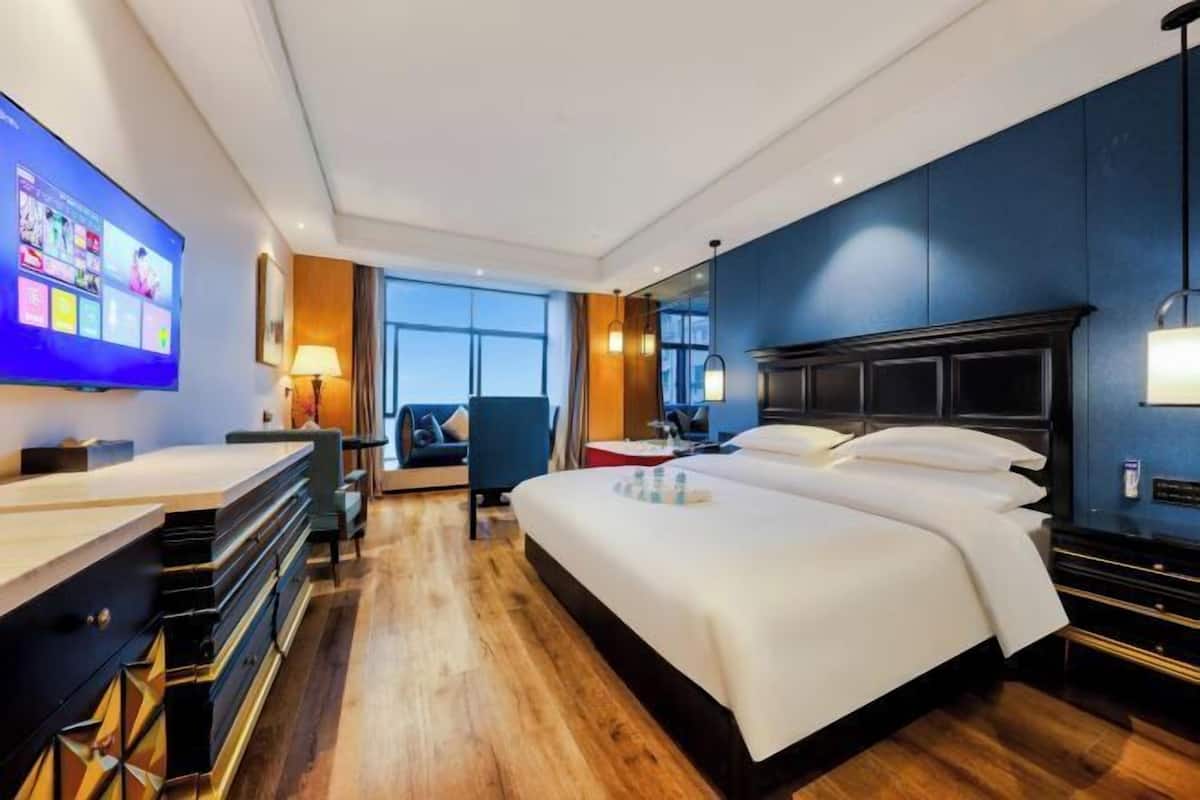 A hotel room with a bed, a desk, a TV, and a view of the outdoors.