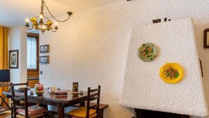 Un'area pranzo con un tavolo e sedie in legno, un camino decorato con piatti e un lampadario.
