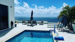 A swimming pool with a view of the ocean, outdoor seating, and a basketball hoop. - Villa Crystal Clear - Luxury Villa with Private Pool (Sint Maarten)