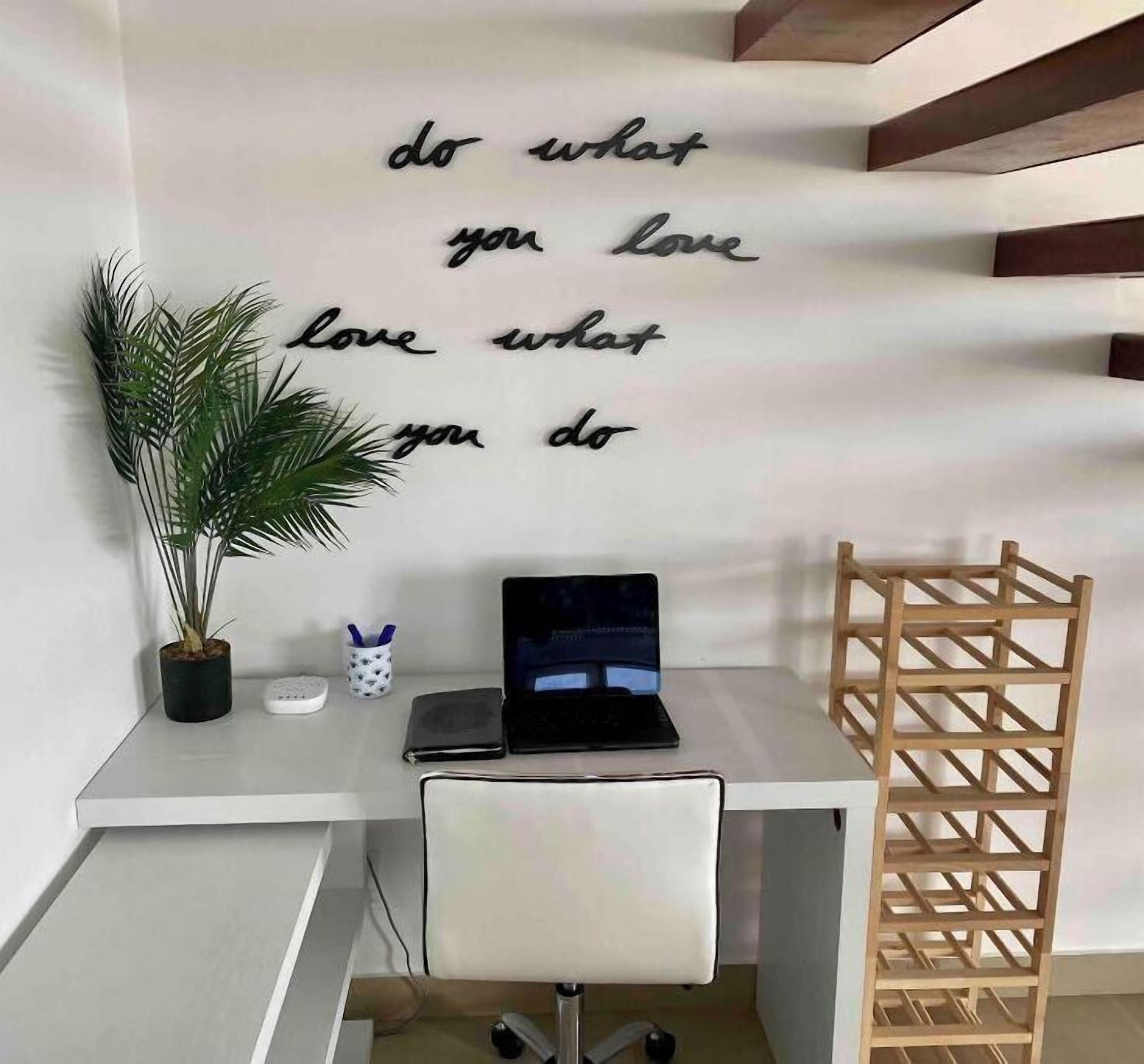 Een werkplek met een bureau, laptop en een inspirerende quote op de muur.