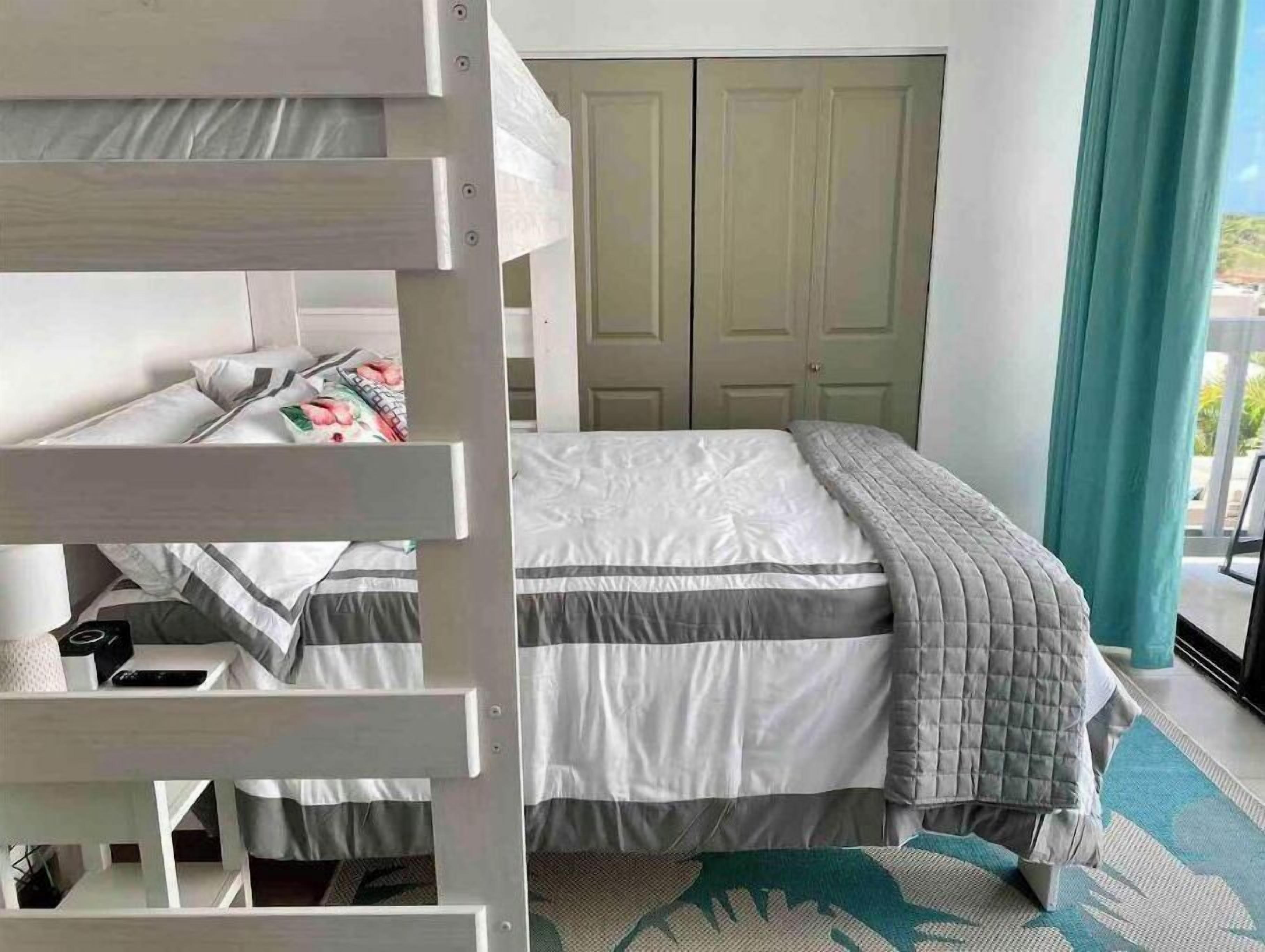 Ein Schlafzimmer mit Etagenbett, Kleiderschrank und einem Fenster mit Vorhängen.