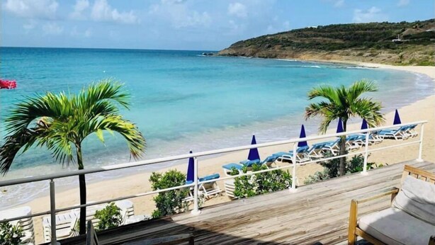A beach view with a wooden deck, palm trees, and lounge chairs. - Villa Crystal Clear - Luxury Villa with Private Pool (Sint Maarten)
