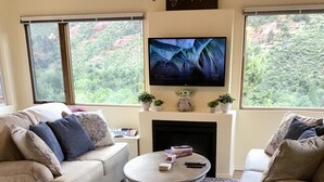 A living room with a fireplace, two sofas, a coffee table, and a TV mounted above the fireplace. - Your Sedona Red Rocks Escape at Oak Creek Canyon! (Sedona)