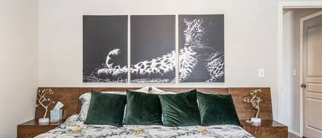 Relax in this serene bedroom with a large bed, two nightstands, and framed photographs above.