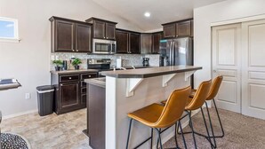 A modern kitchen with dark cabinets, stainless steel appliances, and a central island with bar stools. - Private Wine Country Retreat | South Nampa | Sleeps 10 (Nampa)