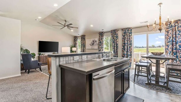 A modern kitchen with a central island, a dining area with a table and chairs, a ceiling fan, and a large window with curtains. - Private Wine Country Retreat | South Nampa | Sleeps 10 (Nampa)