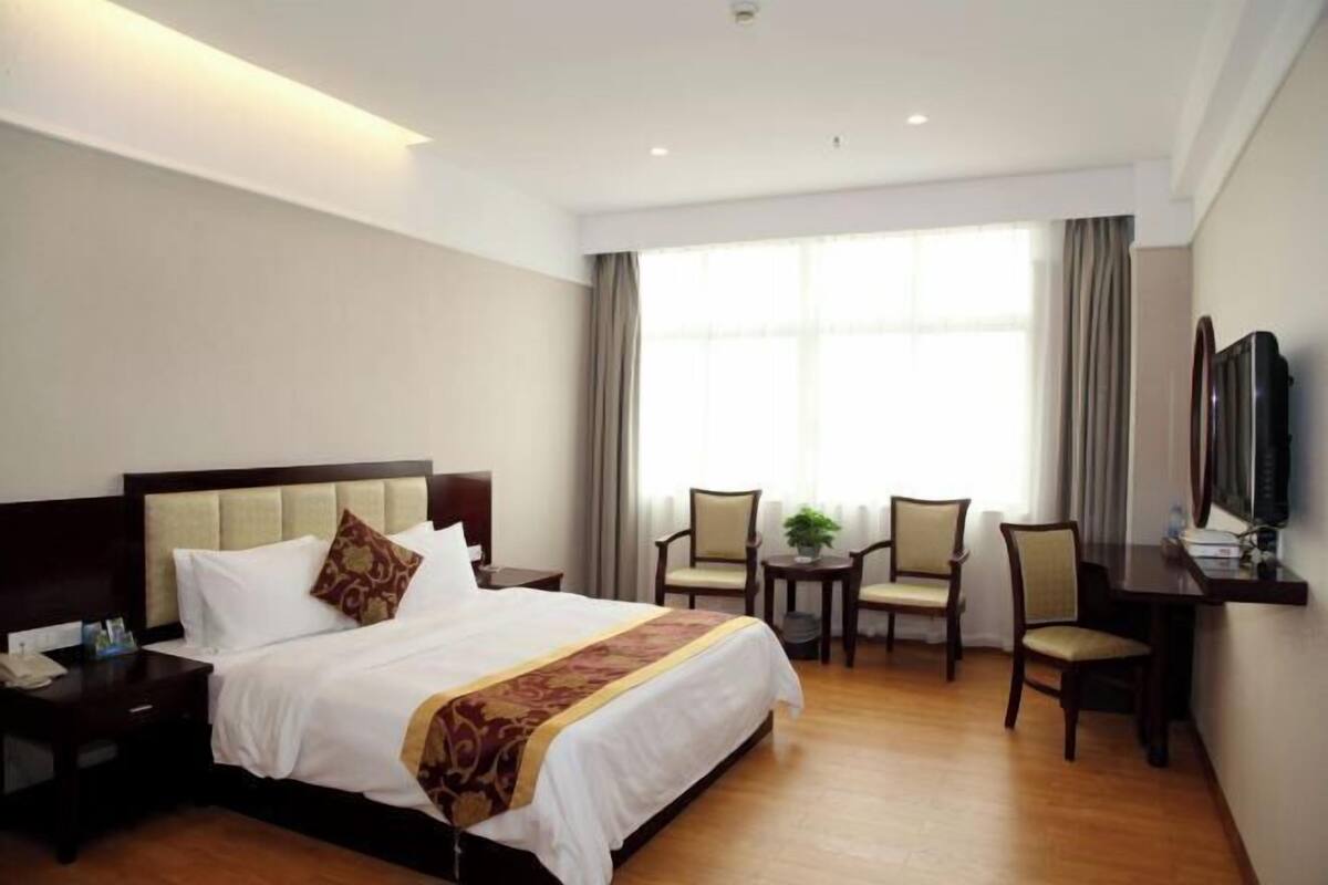 Una habitación de hotel con cama, mesita de noche, televisión y una pequeña mesa con sillas.