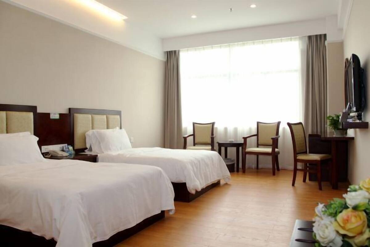 Habitación de hotel con dos camas, un escritorio, una silla y un televisor.