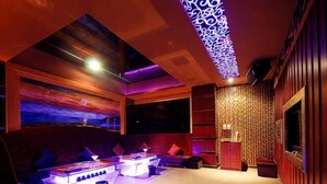 A modern lounge with a sofa, coffee table, and a patterned wall. - Jinjue Hotel (Nearby Train Station) (Huizhou)