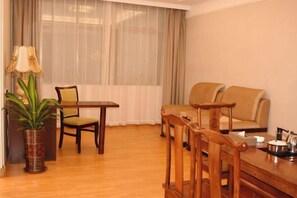 A room with a dining table, chairs, a sofa, a lamp, and a potted plant. - Jinjue Hotel (Nearby Train Station) (Huizhou)