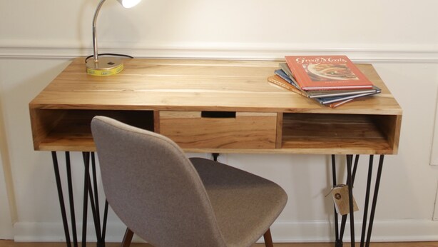 Ein Holztisch mit Lampe, Stuhl und Bücherstapel.