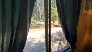 Una habitación con una ventana tapada por cortinas oscuras, una lámpara en una mesita de noche y un equipo de aire acondicionado en la pared.