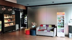 A modern interior with a sofa, ottomans, a vending machine, and a bookshelf. - Jincheng Hotel (Bazhou Shengfang Town) (Bazhou)