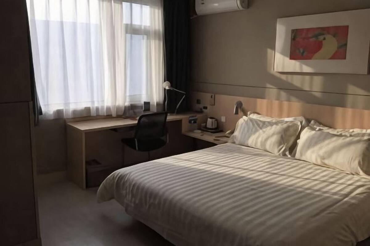Une chambre dâhĂŽtel avec un lit, un bureau, une chaise et un tableau au mur.
