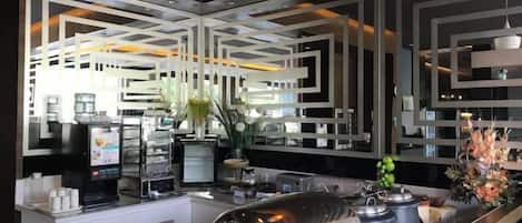 Un área de bar moderna con mostrador, taburetes y una pared decorativa con patrones geométricos.