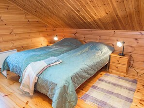 A wooden cabin bedroom with a bed, bedside lamps, and a rug. - Tahkontupa by Interhome (Lapinlahti)