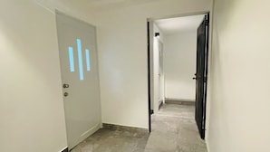 A hallway with a tiled floor, white walls, and doors with a light switch symbol. - 5 Start* *New Lovely apartment in San Juan P.R. (San Juan)