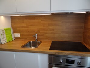 A kitchen with a stainless steel sink, a black induction cooktop, and a built-in oven.