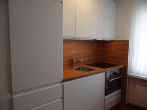 A compact kitchen with a wooden countertop, a stainless steel sink, and a built-in oven.