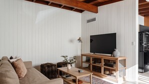 A living room with a sofa, a coffee table, a TV on a wooden stand, and a patterned rug. - NEW: Charming Desert Abode! Centrally located, near UofA & downtown Tucson (Tucson)