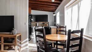 A modern kitchen with a TV, wooden cabinets, and a dining area with a round table and chairs. - NEW: Charming Desert Abode! Centrally located, near UofA & downtown Tucson (Tucson)
