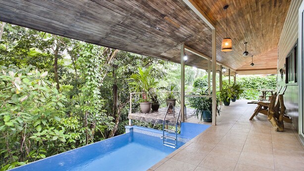 An indoor swimming pool with a wooden ceiling and tiled floor, surrounded by lush greenery. - Tropical Treehouse with Private Pool - 3BR/2.5B (Manuel Antonio)