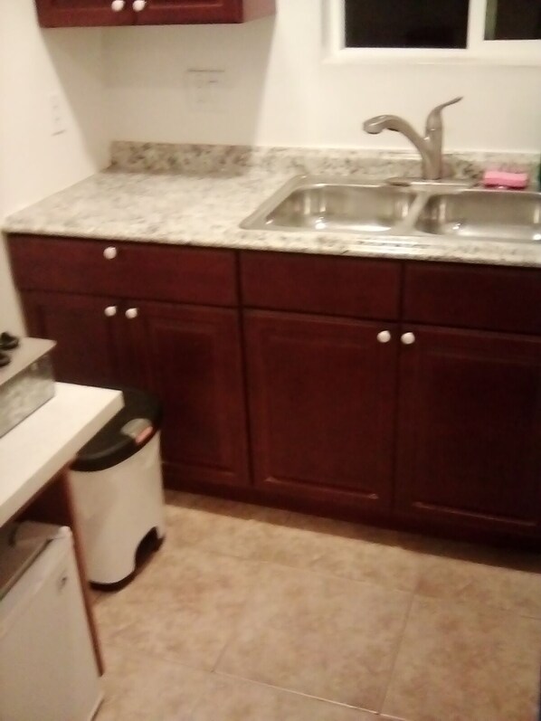Compact kitchen with a granite countertop, stainless steel sink, and dark brown cabinetry.