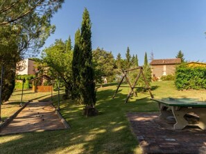 Ein Garten mit einer Holzwentil, einem Boccia-Platz und einem grünen Picknicktisch.