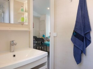 Un baño con un lavamanos blanco, un espejo y una toalla colgada en la pared.