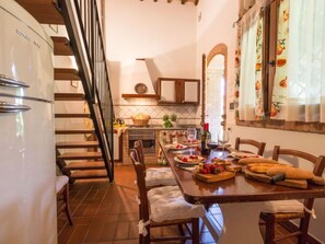 A kitchen with a dining table set for four, a refrigerator, and a staircase leading to another level. - Melograno by Interhome (Peccioli)