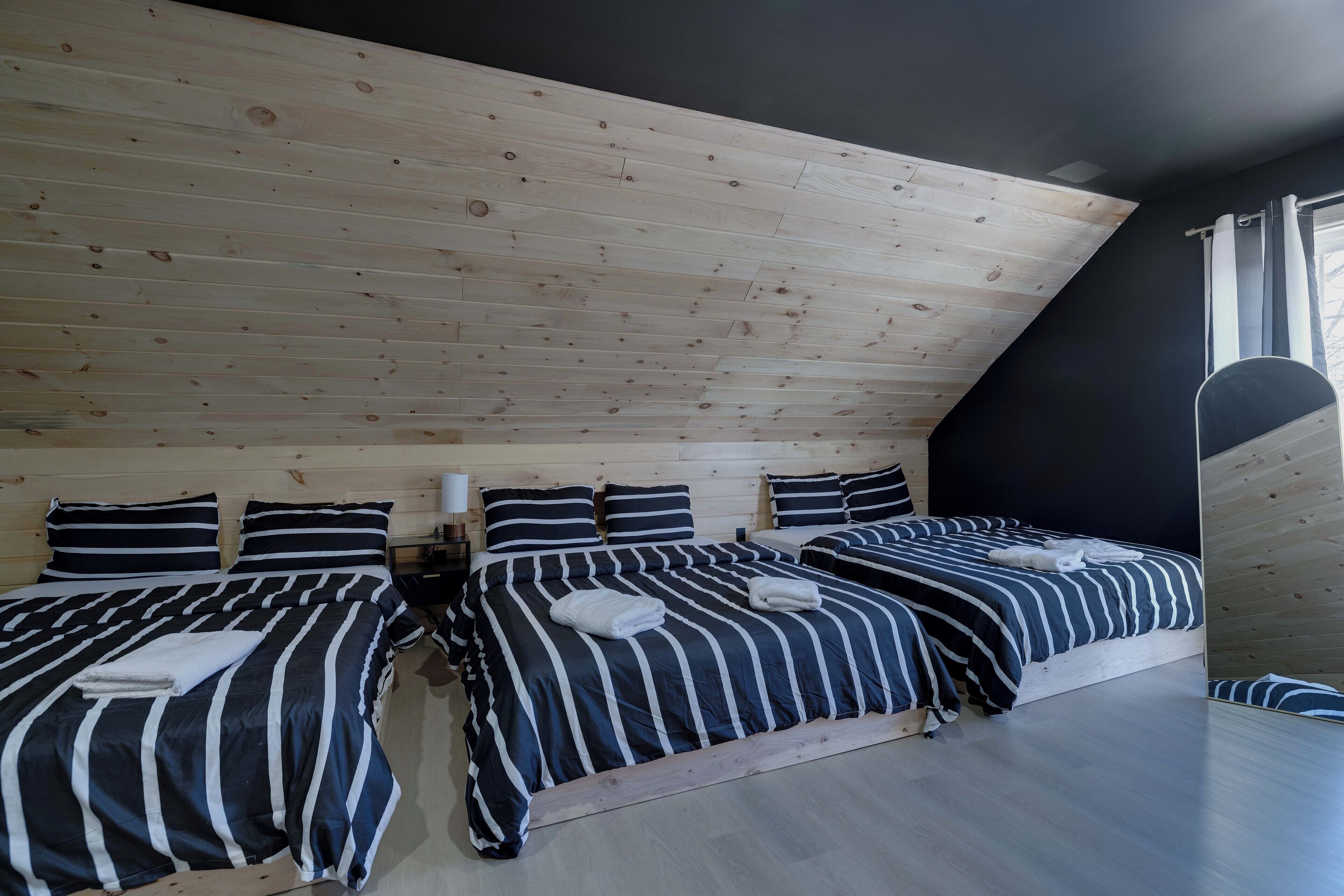 Een kamer met twee bedden, een houten plafond en een raam met gordijnen.