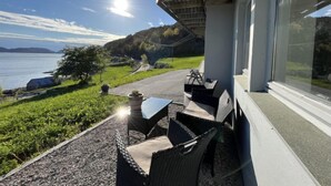A balcony with outdoor furniture overlooking a scenic view of a lake and hills. - Bakkafall by Interhome (Førde)