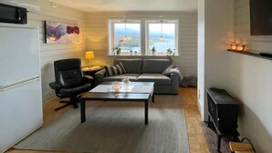 A compact living space with a sofa, a coffee table, a TV, and a view of the sea. - Bakkafall by Interhome (Førde)