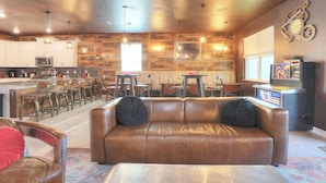 A spacious living area with a leather sofa, wooden accents, and a kitchen in the background.