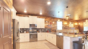 A modern kitchen with white cabinets, stainless steel appliances, and a wooden accent wall.