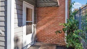 A house with a brick exterior, a white door, and a red and beige awning over the door. - Cozy On Creswell (Shreveport)