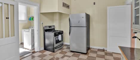 A kitchen with a stove, oven, refrigerator, and a ceiling fan.