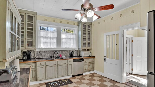 A kitchen with a checkered floor, a ceiling fan, a microwave, and a dishwasher. - Cozy On Creswell (Shreveport)