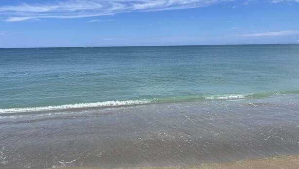 Uma praia com céu claro e águas calmas.