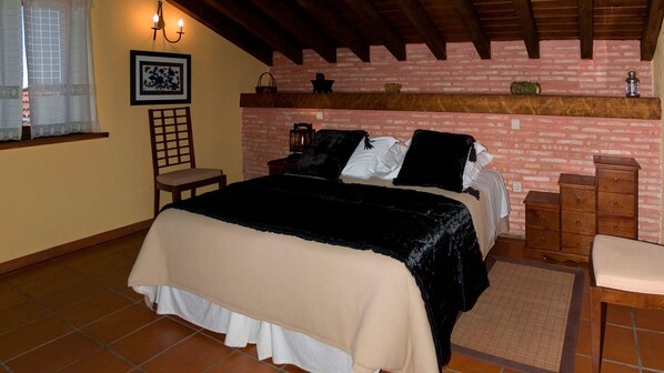 A bedroom with a bed, a chair, a dresser, and a brick wall.
