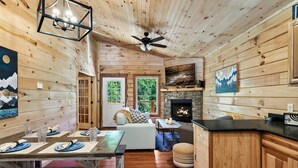 Ein gemütliches Blockhaus-Interieur mit Essbereich, Kamin und Holzwänden.