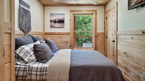 Ein gemütliches Schlafzimmer mit Bett, Fenster und Holzwänden.