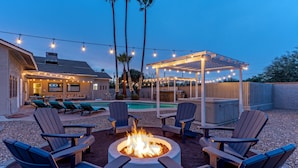An outdoor patio area with Adirondack chairs, a fire pit, and a pool. - ADA Access, One Story, Htd POOL, Spa, Putting Green, Games, Fire Pit, TVs All BRs (Scottsdale)