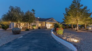 A residential house with a driveway, surrounded by trees and shrubs, at dusk. - ADA Access, One Story, Htd POOL, Spa, Putting Green, Games, Fire Pit, TVs All BRs (Scottsdale)