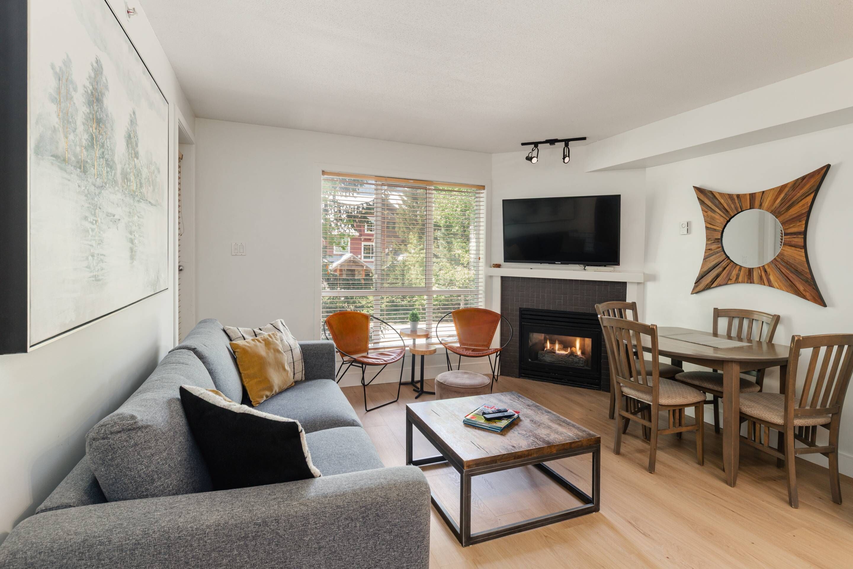 Ein Wohnzimmer mit Sofa, Couchtisch, Fernseher, Kamin und Essbereich.