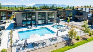 Un hôtel moderne doté d’une piscine, de chaises longues et offrant une vue sur les montagnes.