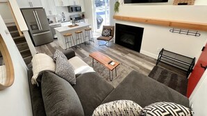 Un salon moderne avec un canapé gris, une table basse et un téléviseur fixé au mur.