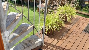 A wooden staircase with a metal handrail, leading to a deck area with potted plants. - The Sky House by the bay (Wynnum)